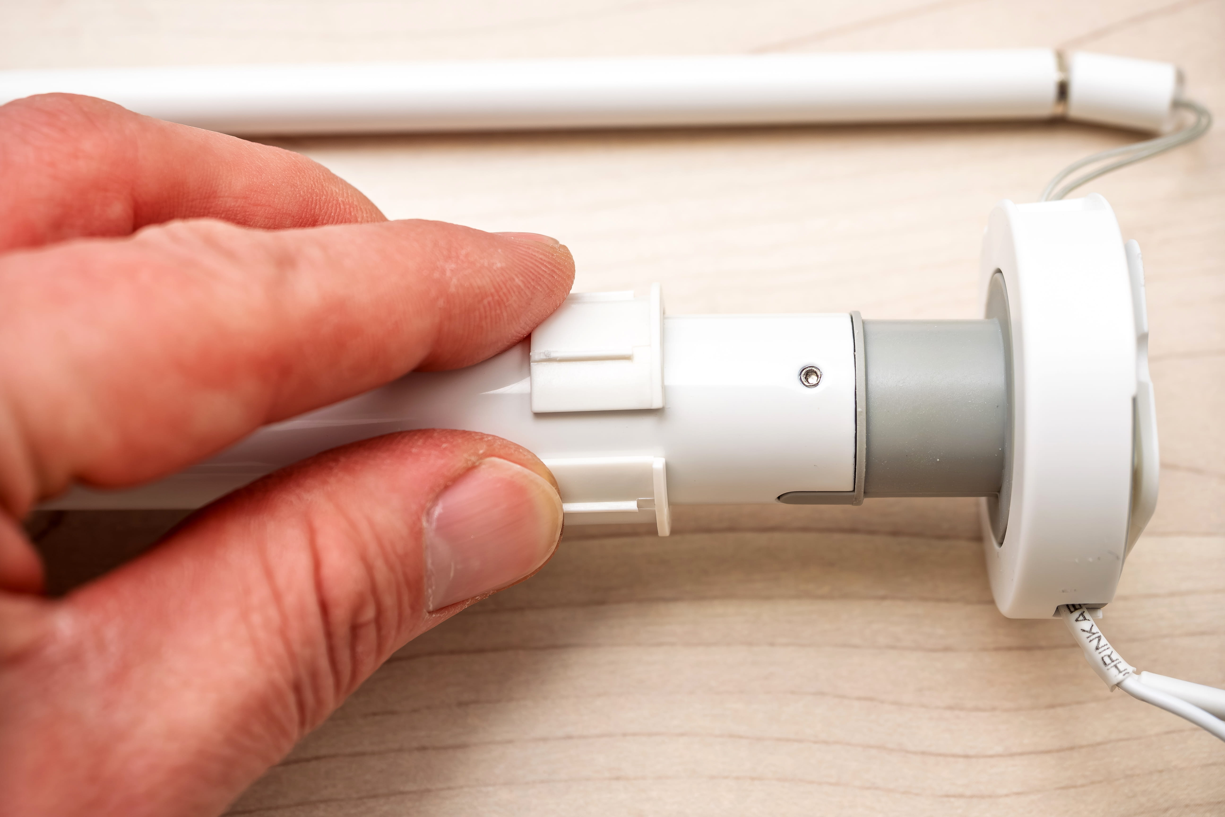 Hand adjusting a smart radiator valve on a radiator, with a pencil above