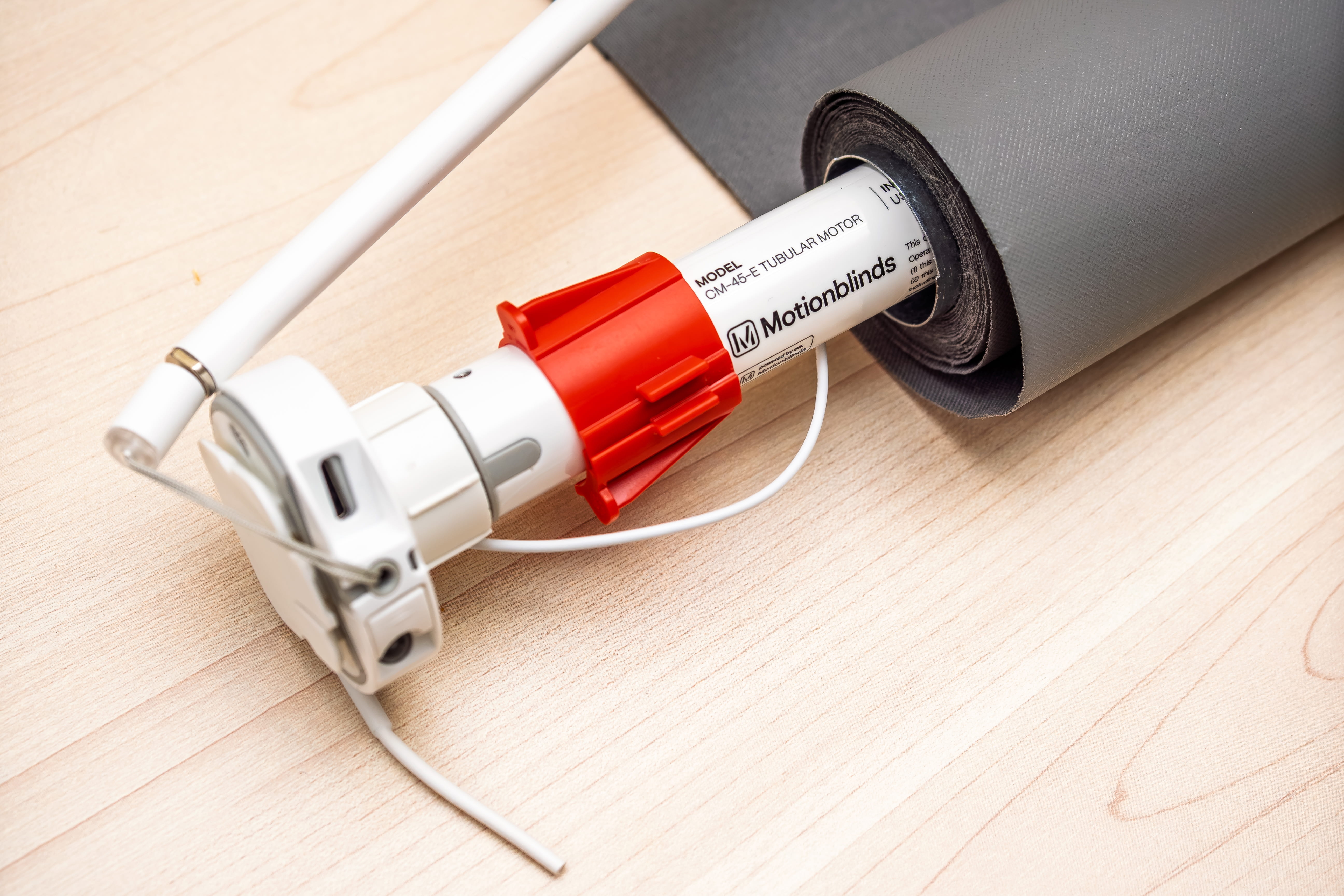 Close-up of a cordless drill with red chuck drilling into a light wood board