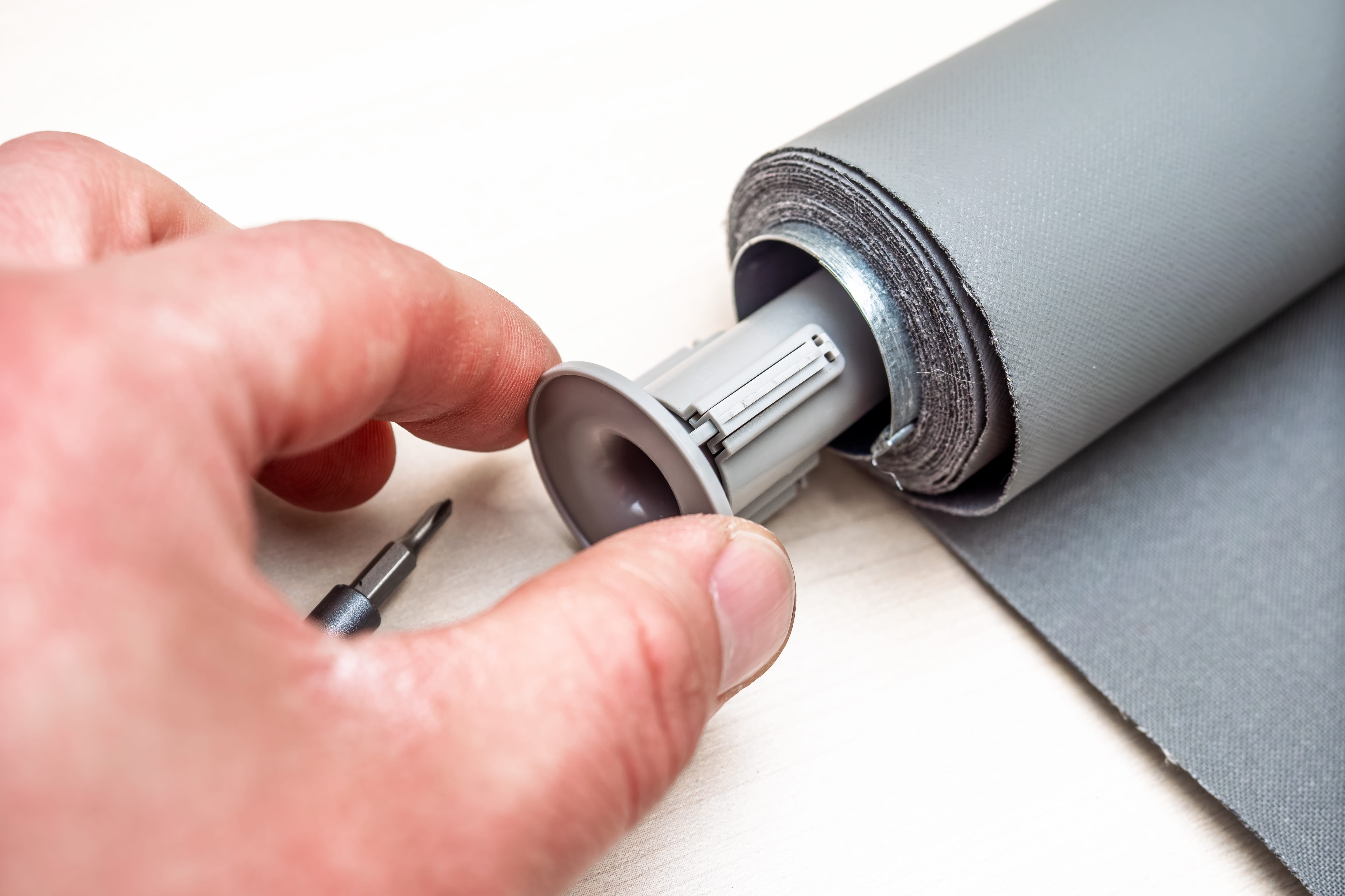 Hand inserting a metal rod into a cylindrical roller mechanism