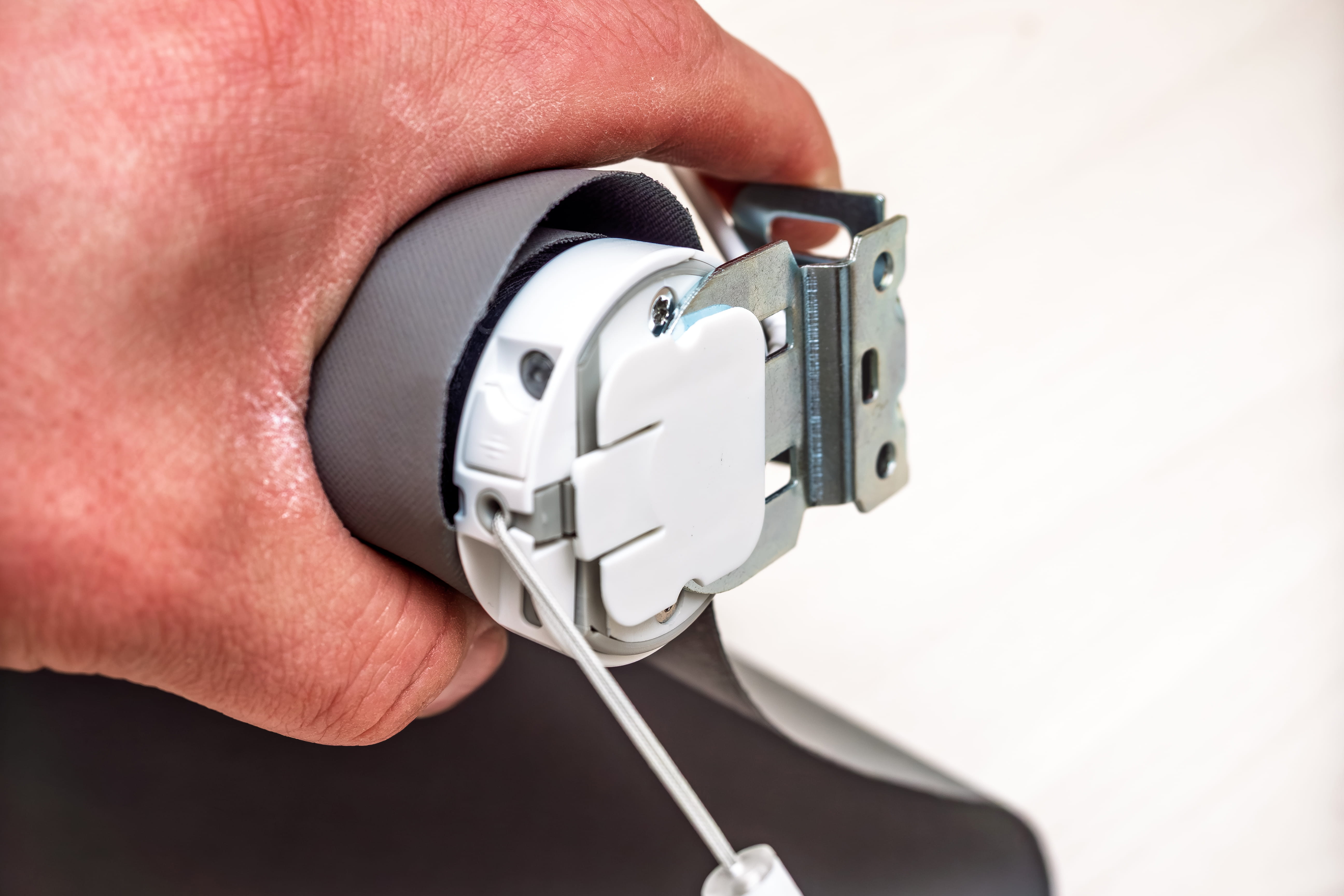 Hand holding a roller blind motor with a hanging pull cord
